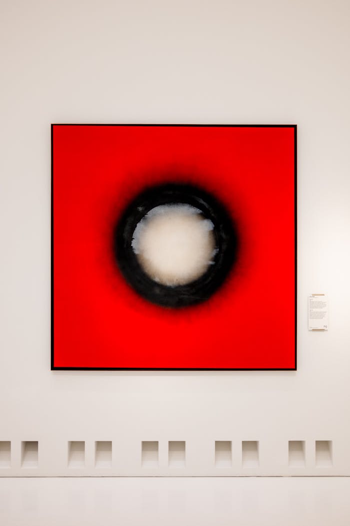 Offerings Striking abstract artwork with bold red and black hues on display in a modern art gallery.