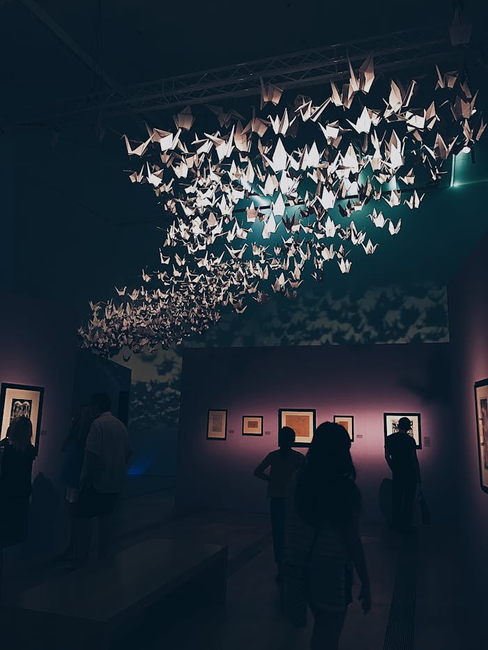 Offerings Elegant origami display in a dimly lit Singapore art gallery with a crowd.